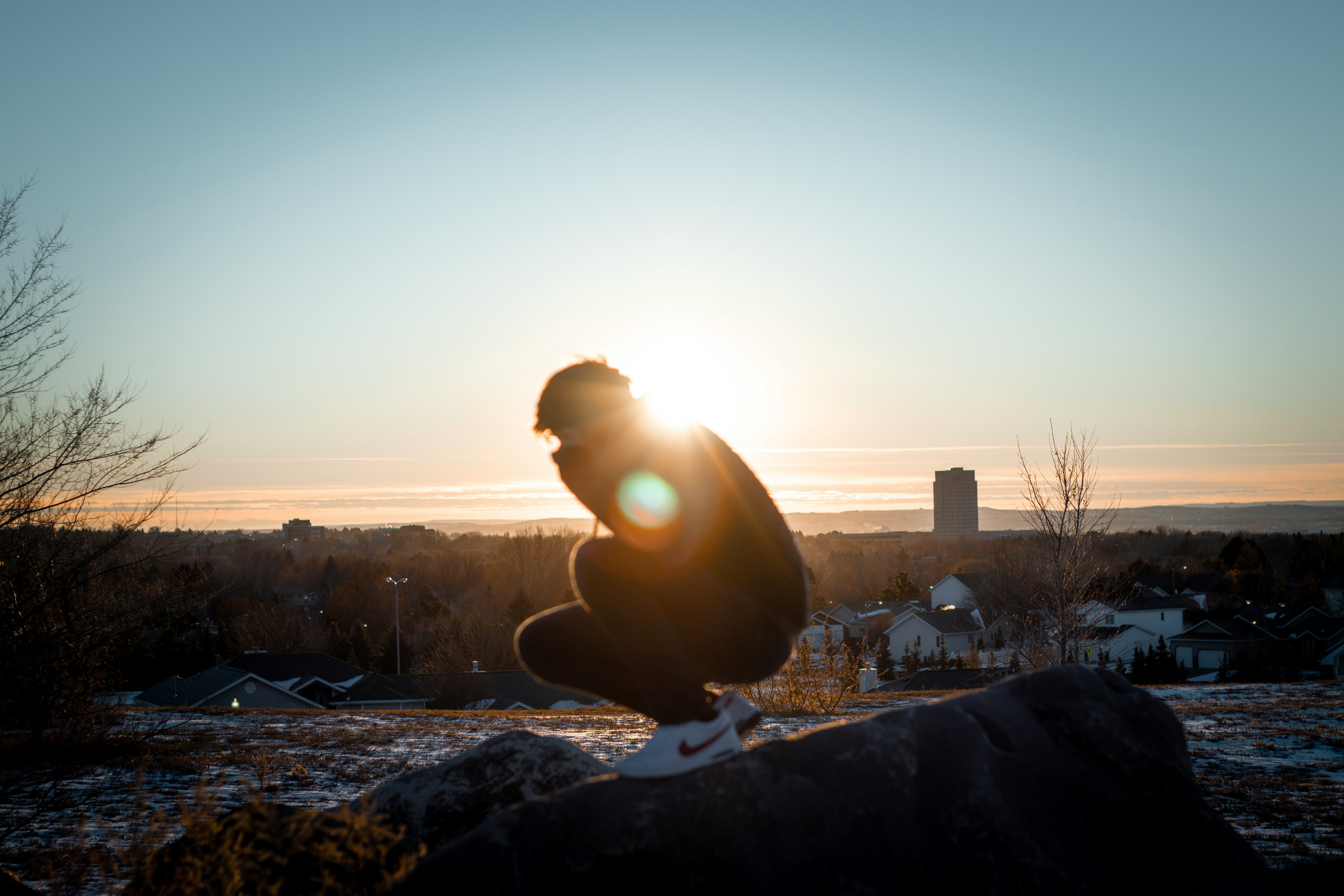 man in black jacket sitting on rock during daytime